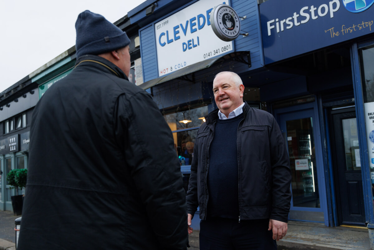 two people talking in front of shops