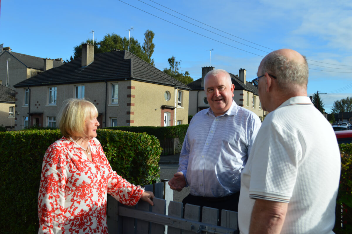 3 people talking at a garden fence